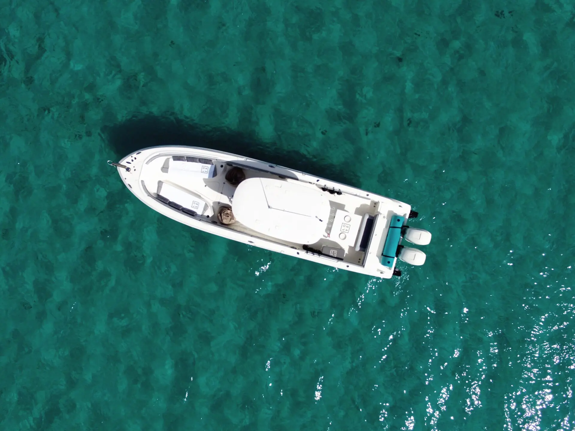 Un bateau blanc vu d'en haut, à l'arrêt sur l'eau turquoise